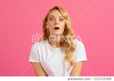 Shocked millennial blonde woman opening her mouth over pink background Shocked millennial blonde woman opening her mouth over pink background 112723309