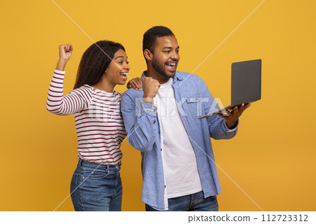 Online Win. Joyful African American Couple Holding Laptop And Celebrating Success 112723312