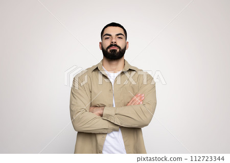 Self-assured man with a neat beard standing arms crossed 112723344