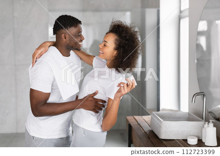 Happy black couple embraces in the bathroom sharing skincare moments 112723399
