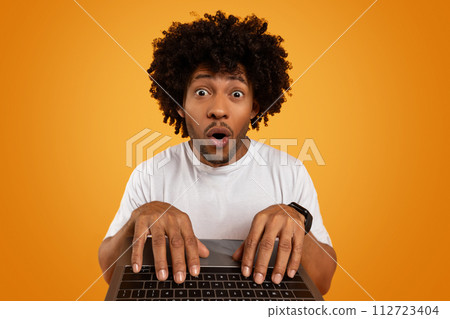 Amazed young african american guy typing on laptop keyboard 112723404