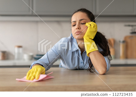 Tired young woman cleaning kitchen countertop 112723435