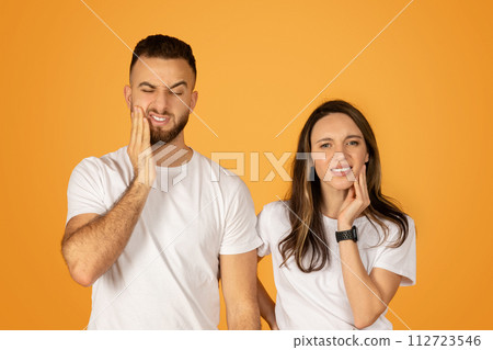 Young man and woman in white shirts showing toothache discomfort Young man and woman in white shirts showing toothache discomfort 112723546