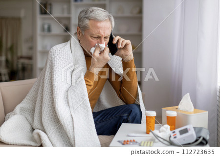 Sick senior man holding cellphone and calling doctor Sick senior man holding cellphone and calling doctor 112723635