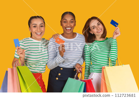 Multiracial women holding credit card and shopping bags 112723681