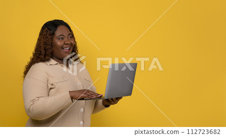 Positive chubby african american woman using laptop 112723682