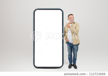 Smiling Senior Man Pointing At Big Smartphone With Blank Screen Smiling Senior Man Pointing At Big Smartphone With Blank Screen 112723688