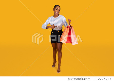 Joyful black woman pointing at shopping bag in her hand 112723727