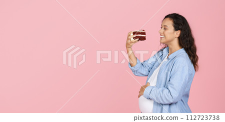 Glad millennial pregnant woman holding piece of cake 112723738