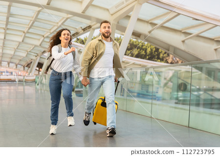 Young couple in rush running with yellow suitcase at the airport Young couple in rush running with yellow suitcase at the airport 112723795