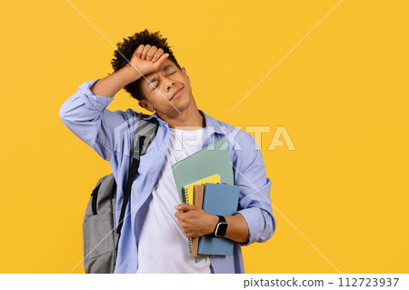 Stressed black student guy with books, overwhelmed by study load 112723937