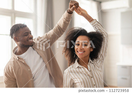 Happy African American married couple enjoying romantic weekend dance indoors 112723958