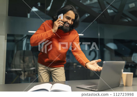 Indian man manager multitasking at modern dark office 112723998