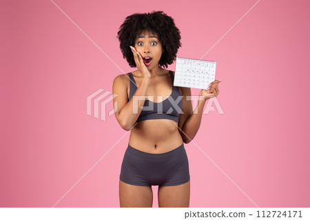 Surprised black woman holding personal tracking calendar 112724171