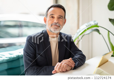 Confident senior male executive with a neatly trimmed beard, wearing a black blazer 112724174