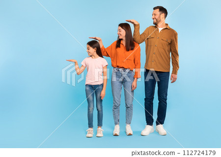 Parents And Daughter Measuring Each Other's Height With Hand, Studio 112724179