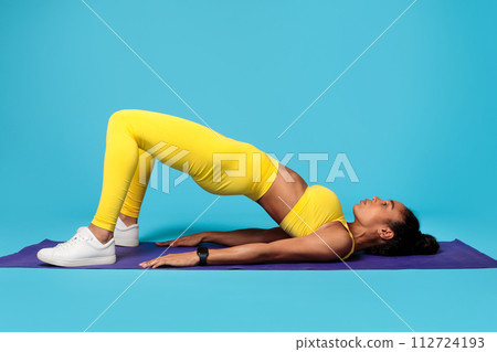African lady in sportswear making bridge pose on mat, studio African lady in sportswear making bridge pose on mat, studio 112724193