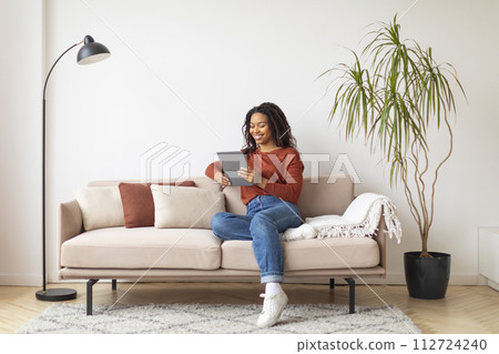 Beautiful young black woman using digital tablet at home 112724240