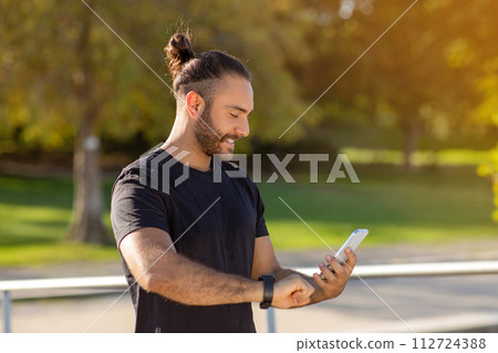 man wearing fitness tracker checks heart rate on smartphone outdoor man wearing fitness tracker checks heart rate on smartphone outdoor 112724388