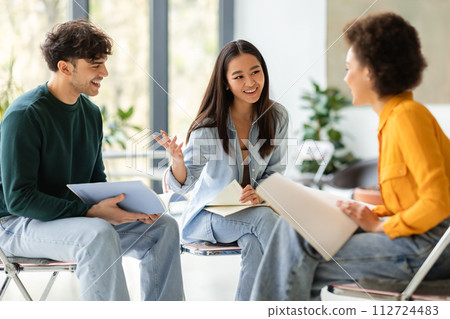 Multiracial students discussing notes in lively group study session 112724483