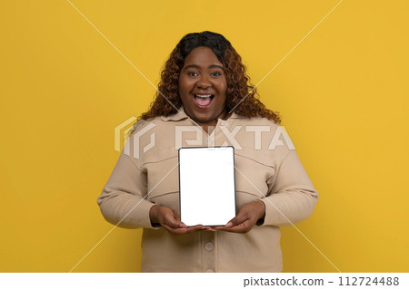 Positive chubby african american woman showing tablet with blank screen 112724488