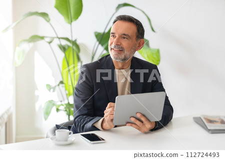 Optimistic mature businessman with a tablet in hand and a joyful expression 112724493