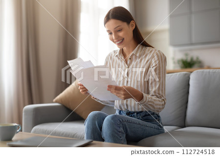 Happy woman reading letters at home Happy woman reading letters at home 112724518