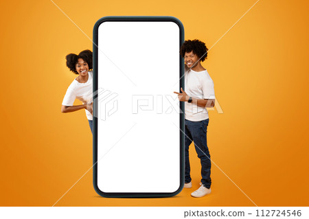 Cool young black man and woman pointing at big smartphone 112724546