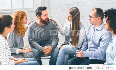 Therapy Group Members Comforting Upset Man On Community Meeting In Rehab Therapy Group Members Comforting Upset Man On Community Meeting In Rehab 112724629