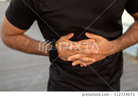 Cropped of man grips stomach in discomfort during workout outdoors 112724673