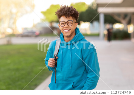 Cheerful brazilian student guy standing with his backpack outside Cheerful brazilian student guy standing with his backpack outside 112724749