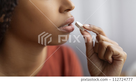 Unrecognizable Young Black Woman Taking White Pill At Home, Closeup 112724777