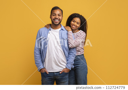 Happy Couple. Smiling Black Man And Woman Posing Over Yellow Background Happy Couple. Smiling Black Man And Woman Posing Over Yellow Background 112724779