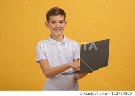 Portrait Of Smiling Teen Boy Holding Laptop Computer In Hands 112724809