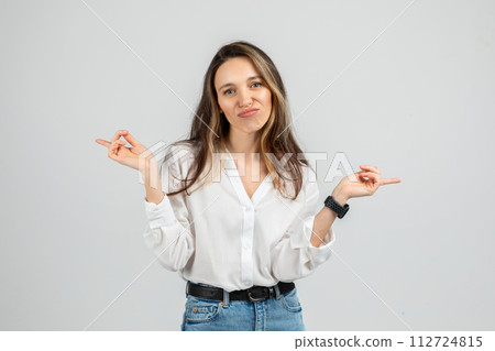A young woman wearing a white blouse and blue jeans with a smartwatch makes an uncertain expression A young woman wearing a white blouse and blue jeans with a smartwatch makes an uncertain expression 112724815