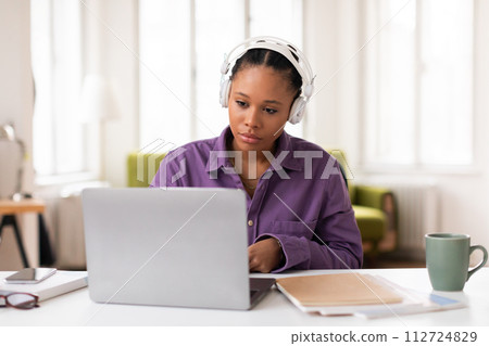 Student in headphones intently using laptop 112724829