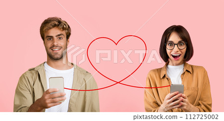 A young man in a beige jacket and white t-shirt smiles with his phone 112725002