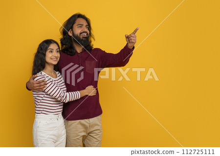 Smiling millennial indian couple pointing at copy space Smiling millennial indian couple pointing at copy space 112725111