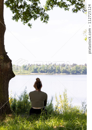 Woman Embracing Serenity at Lakeside under the Canopy 112725124