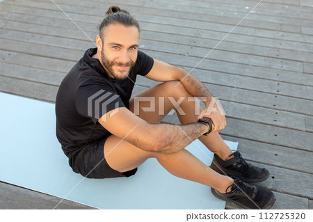 athlete guy enjoys workout break sitting on mat outdoor 112725320
