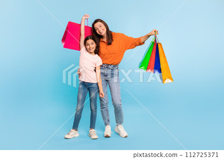Happy young mother and daughter posing with shopping bags, studio 112725371