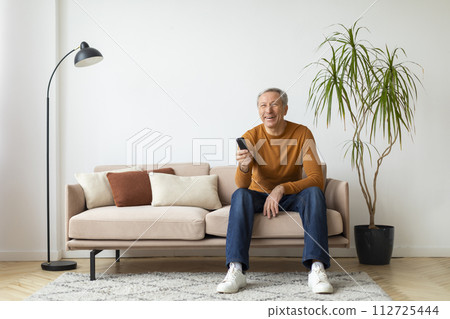 Happy senior man with remote control in his hand Happy senior man with remote control in his hand 112725444