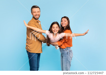 Parents holding little daughter while she pretends to fly, studio Parents holding little daughter while she pretends to fly, studio 112725447