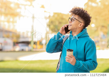 guy in eyeglasses engages in phone conversation amid urban surroundings 112725484