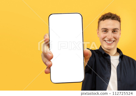 Cheerful young man showing smartphone with blank display 112725524