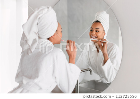 African lady practices daily dental routine brushing teeth at bathroom African lady practices daily dental routine brushing teeth at bathroom 112725556