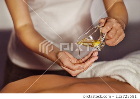 Masseur pouring aroma oil on hand, preparing for massage 112725581