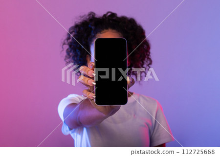 Lady showing smartphone with blank screen, covering face against neon background 112725668