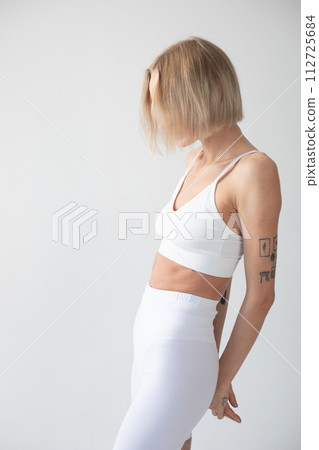 Blonde girl posing on a white background in a top and leggings 112725684