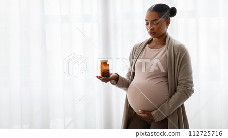Pregnant african american lady holding jar with pills 112725716